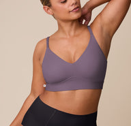 India poses in the Bliss Triangle Bralette in Eclipse paired with the Bliss Boyshort in Black, facing slightly sideways with her hand behind her head. The bralette’s shaping and soft structure are shown in contrast with the high-rise black boyshort. sizing: India wears size XL