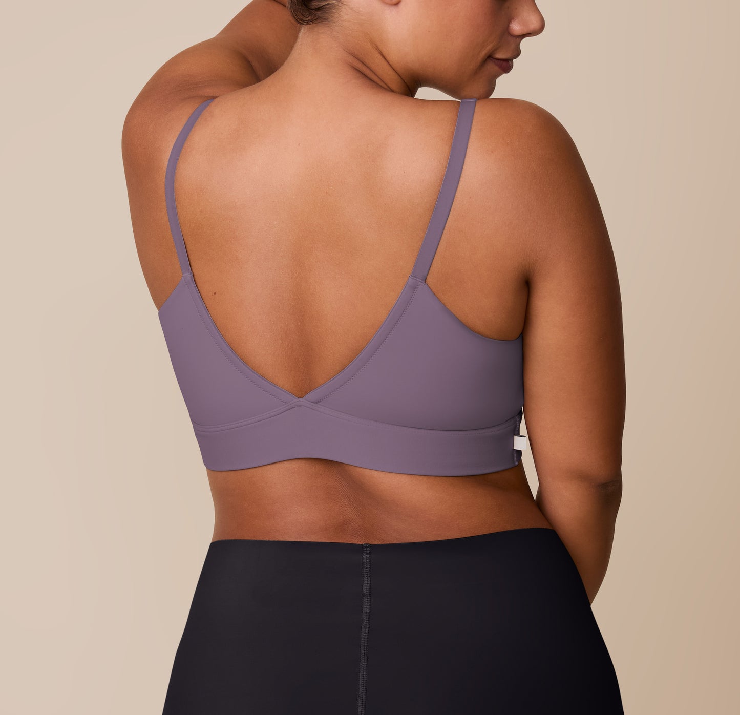 India turns away from the camera, displaying the back of the Bliss Triangle Bralette in Eclipse and the Bliss Boyshort in Black. The deep V-back and wide underband of the bralette are paired with the full-coverage, high-rise silhouette of the boyshort in Black.