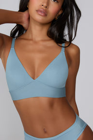 Close-up on a light gray studio backdrop of Amber in the Bliss Triangle Bralette in Poolside, focusing on the deep V neckline, front-adjusting straps, and smooth microfiber fabric.