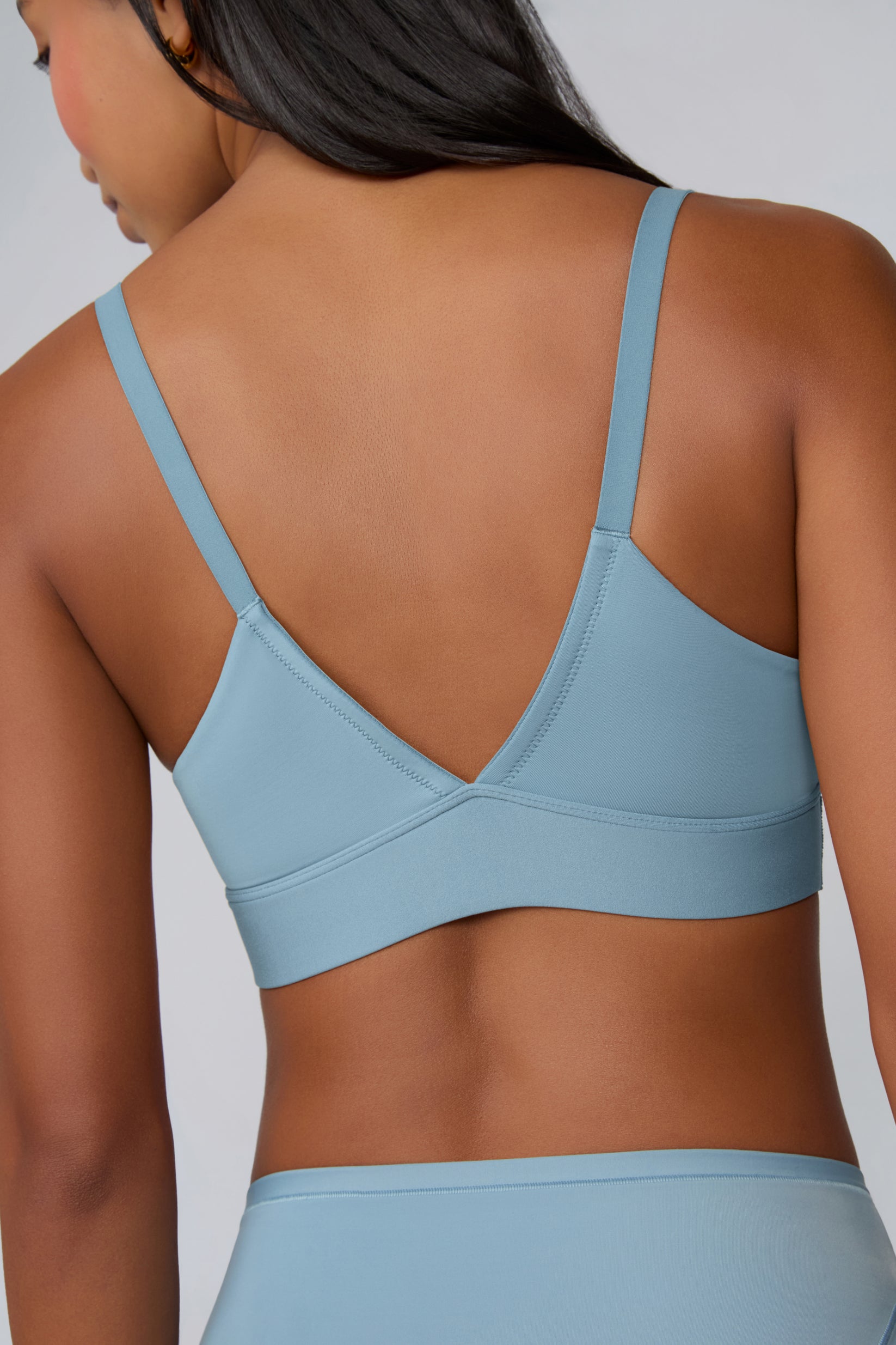 Close-up back view on a light gray studio backdrop of Amber in the Bliss Triangle Bralette in Poolside, focusing on the V-back shape, thin adjustable straps, and soft microfiber fabric.