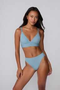 Front-facing studio image of Amber on a light gray backdrop wearing the Bliss Triangle Bralette in Poolside with the matching bikini brief, showing the deep V front, wide wireless band, and smooth microfiber finish.