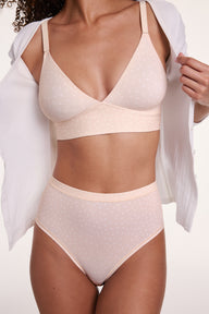 In a studio setting, Courtney wears the Bliss Triangle Bralette in Champagne Fizz with the Bliss Highwaist Brief in Champagne Fizz, showing the deep V neckline, front-adjusting straps, wireless band for lift, and soft microfiber fabric with a subtle dotted pattern.