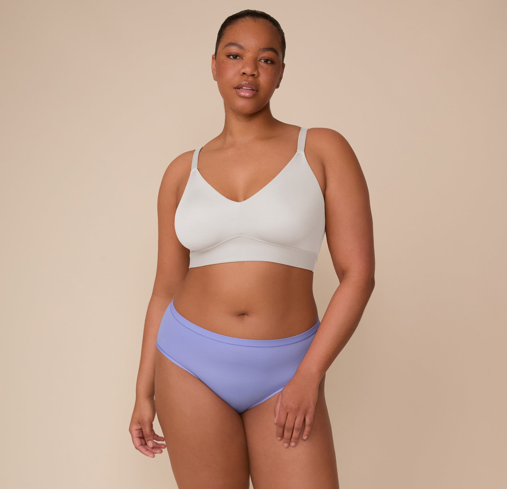 Full-body shot of Zarria wearing the Bliss Triangle Bralette in Frost and Bliss Hiphugger in Dusk. She stands with a relaxed pose, emphasizing the flattering, smooth fit of both pieces.