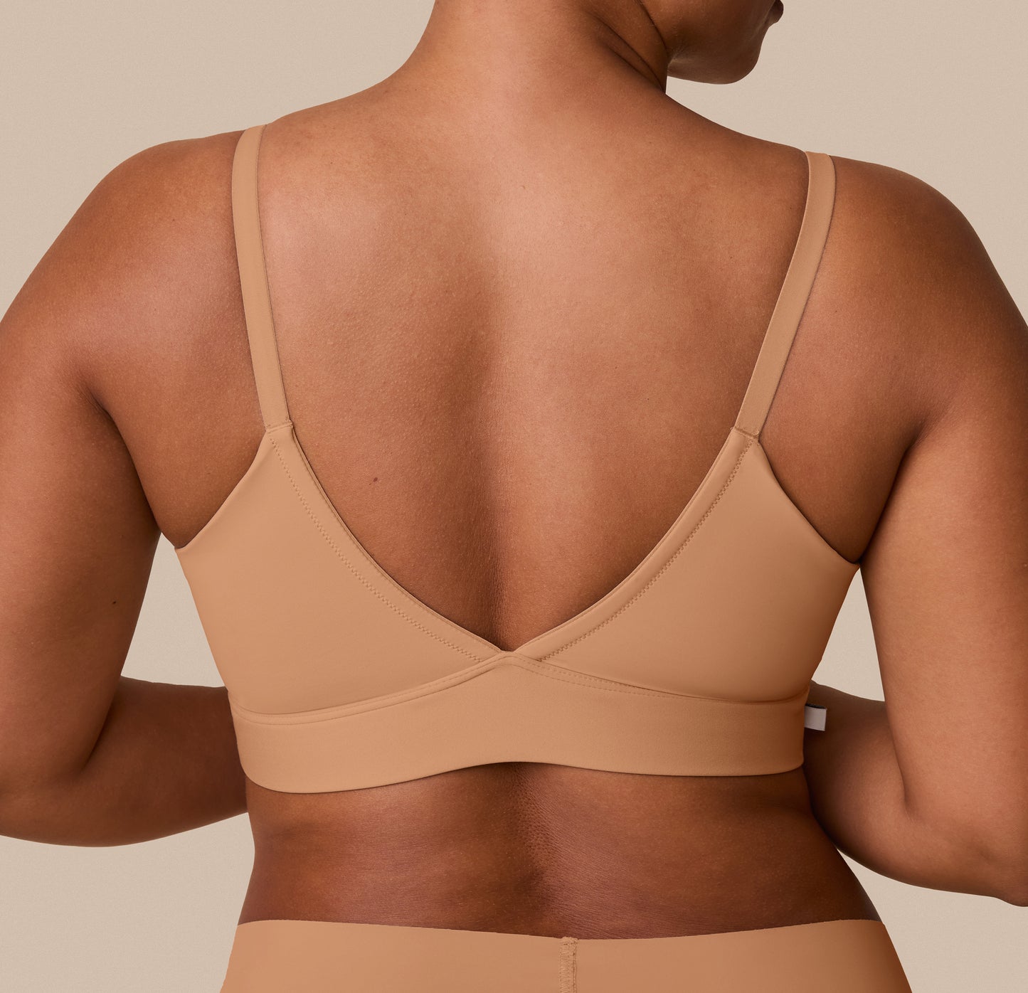 A close-up of the back of India wearing the Bliss Triangle Bralette, emphasizing the smooth, adjustable straps and flexible band.