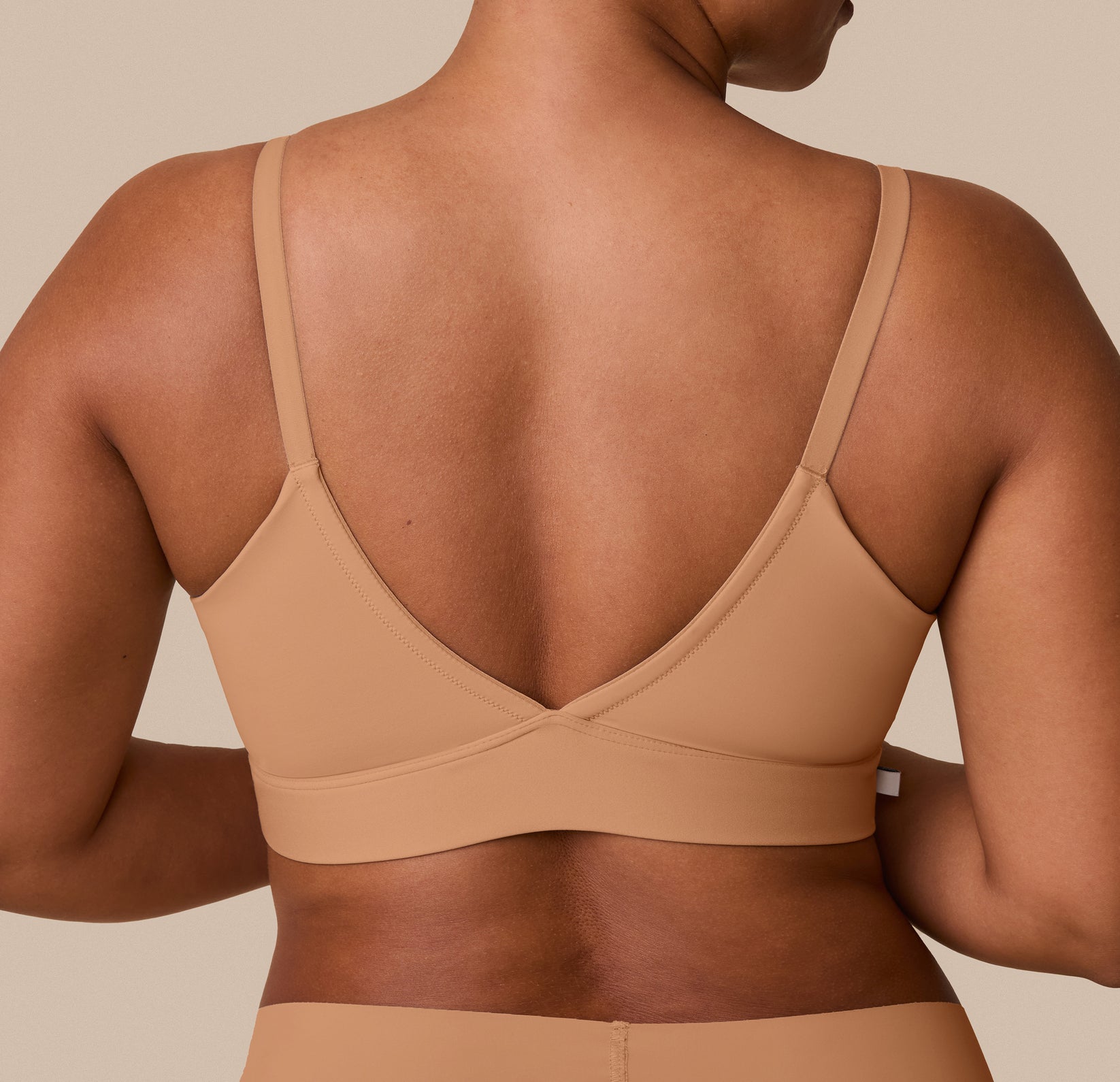 A close-up of the back of India wearing the Bliss Triangle Bralette, emphasizing the smooth, adjustable straps and flexible band.