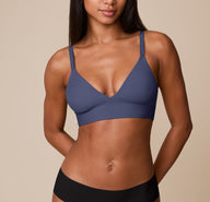 Ally wears the Bliss Triangle Bralette in Twilight. The deep V-neckline and wide underband offer a flattering fit with gentle support, while the rich slate-blue shade adds a calming, elevated touch. sizing: Ally wears size XS