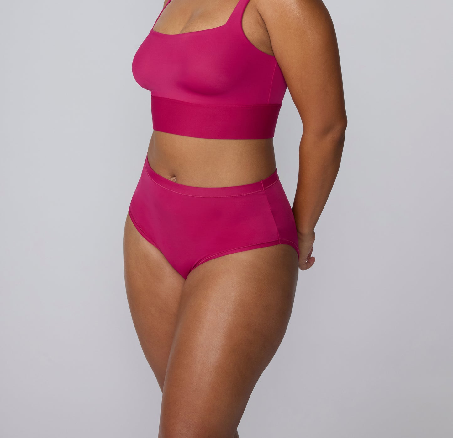 Angled full-body view on a white studio backdrop of a model wearing the Bliss Square Neck Bralette and Bliss High Waist in Winterberry, showing the coordinated set and streamlined design. sizing: India wears size Large