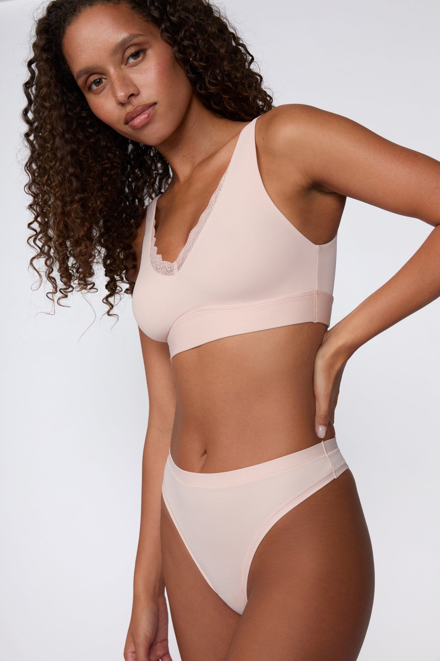 On a white studio backdrop, a side view of the Bliss Lace Bralette in Ember Rose shows the wireless design, wide straps, and smooth band for everyday comfort.