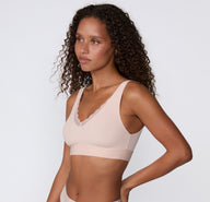 On a white studio backdrop, a side view of the Bliss Lace Bralette in Ember Rose shows the wireless design, wide straps, and smooth band for everyday comfort.