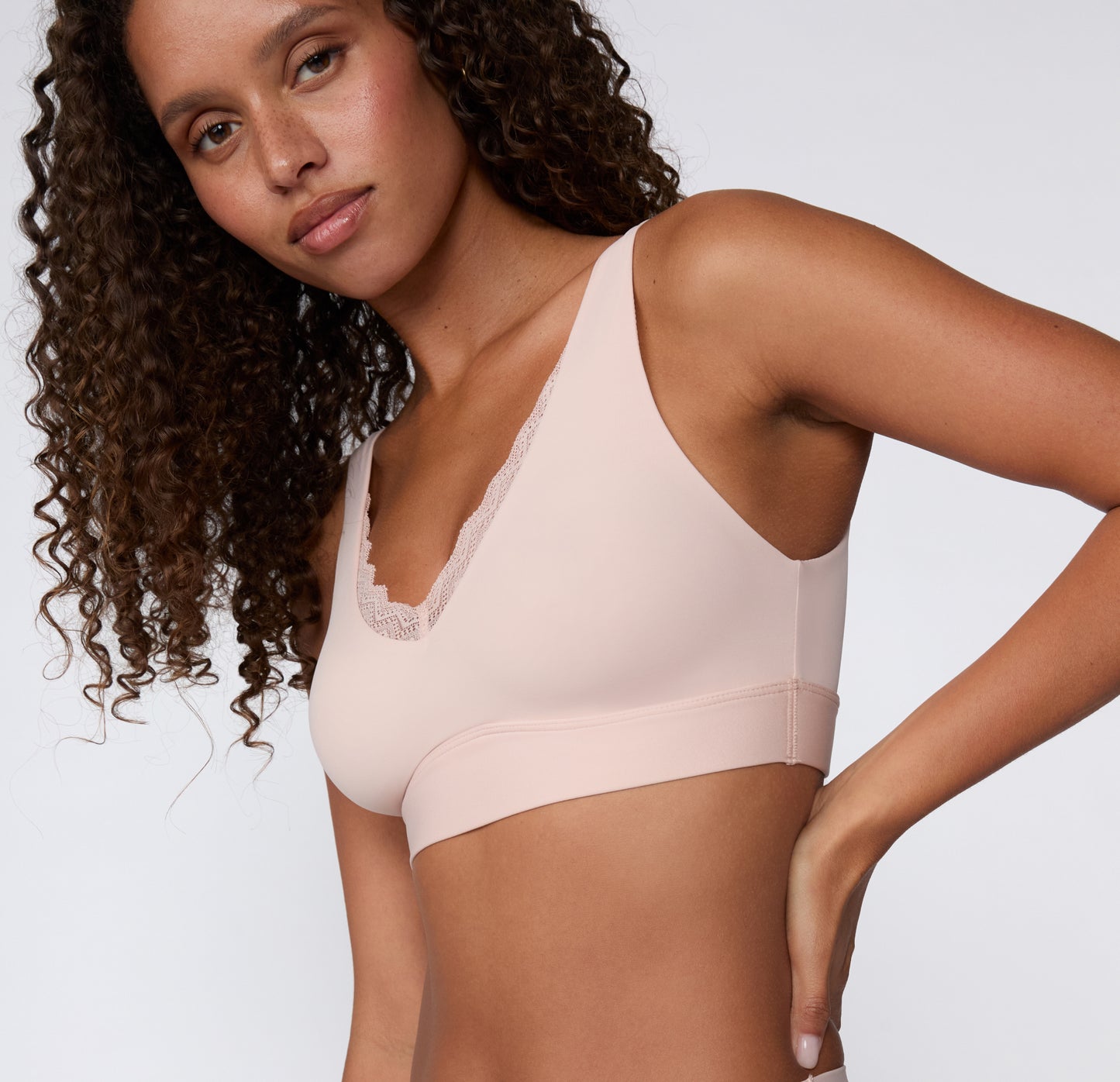 Angled front view on a white studio backdrop of a model wearing the Bliss Lace Bralette in Ember Rose, featuring the soft microfiber fabric and lace-trimmed neckline. sizing: Courtney wears size Small