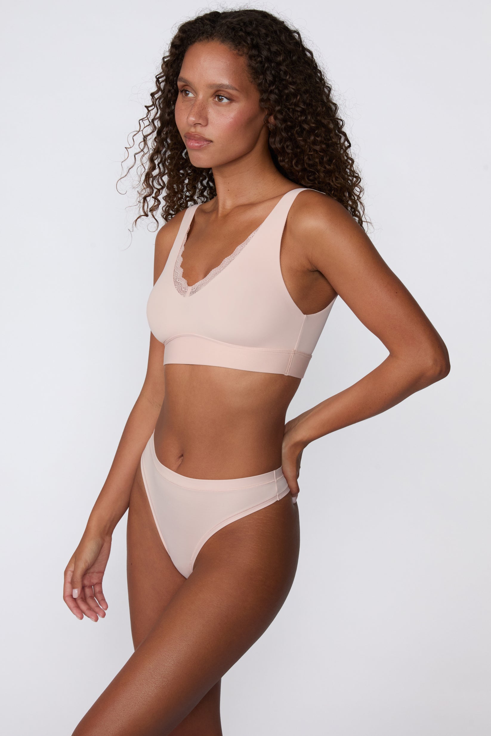 On a white studio backdrop, a side view of the Bliss Lace Bralette in Ember Rose shows the wireless design, wide straps, and smooth band for everyday comfort.