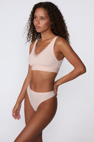 On a white studio backdrop, a side view of the Bliss Lace Bralette in Ember Rose shows the wireless design, wide straps, and smooth band for everyday comfort.