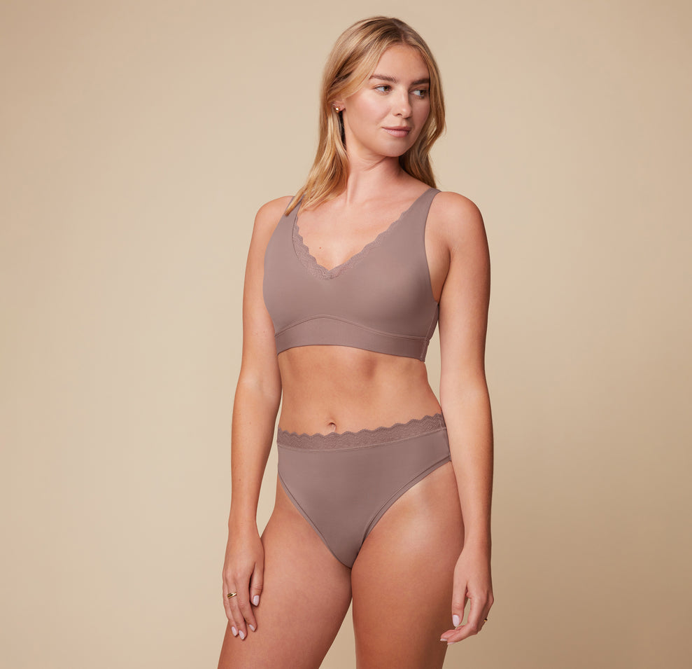 Megan posing in the Bliss Lace Bralette and Bliss Highwaist Lace Thong in Mauve. The front-facing image highlights the soft, comfortable design of both the bralette and the thong.