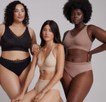 Three models showcasing the Bliss Lace Collection in different shades. From left to right: Bianca wearing the Bliss Lace Bralette and Bliss Lace Highwaist Brief in Black, the second model wearing the Bliss Lace Halterneck Bralette and Bliss Lace Highwaist Brief in Beige, and the third model in the Bliss Lace Bralette and Bliss Lace Highwaist Brief in Mauve. The image highlights the comfortable, supportive fit and lace detailing of the collection, featuring diverse skin tones and body types.