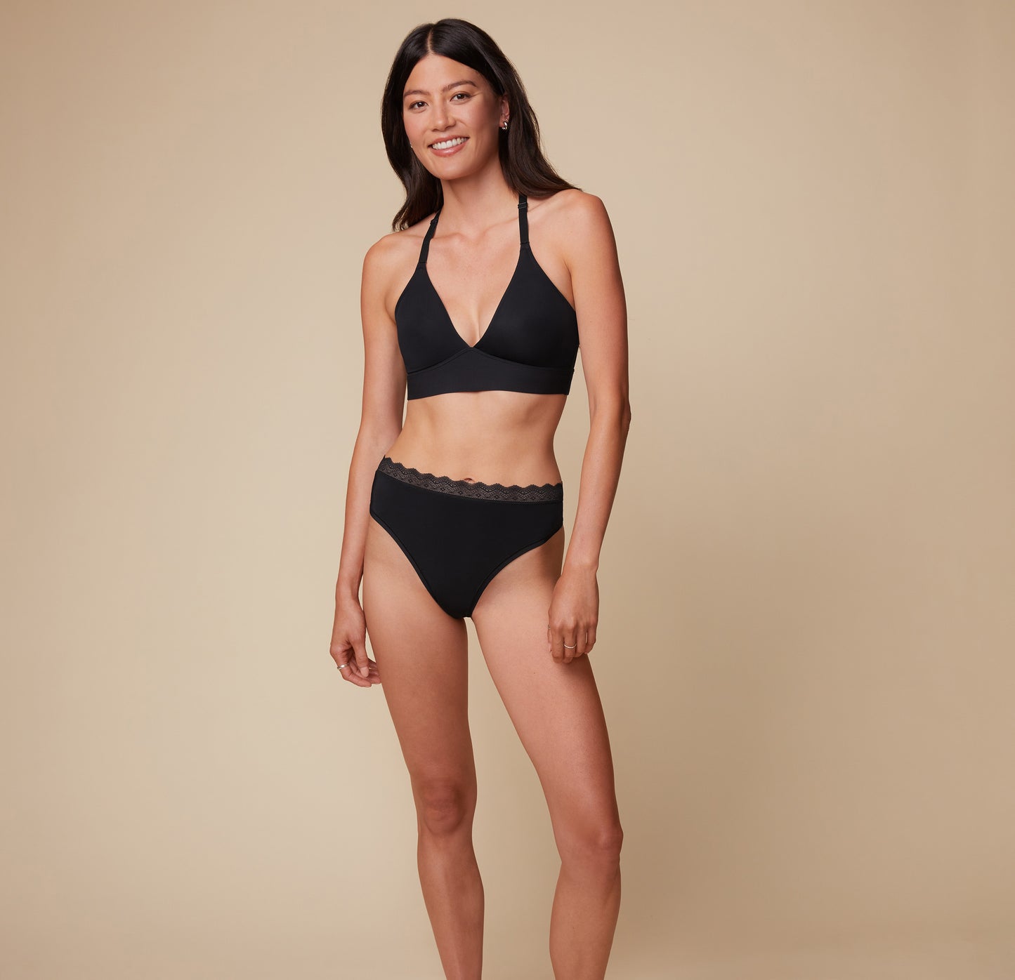 Model Anna wearing the Bliss Lace Halterneck Bralette in Black, paired with the matching Bliss Highwaist Lace Thong. She stands facing forward, showcasing the supportive fit of the halterneck bralette and the sleek design of the highwaist thong. sizing: Sizes L-4XL have higher center in front for additional support.