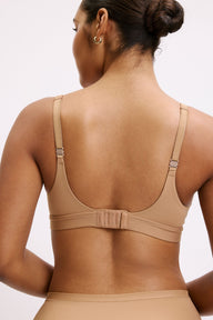 Amber wears the Bliss Plunge Adjustable Bra in Tan from the back, showing adjustable straps, hook-and-eye closure, and a smooth microfiber band.