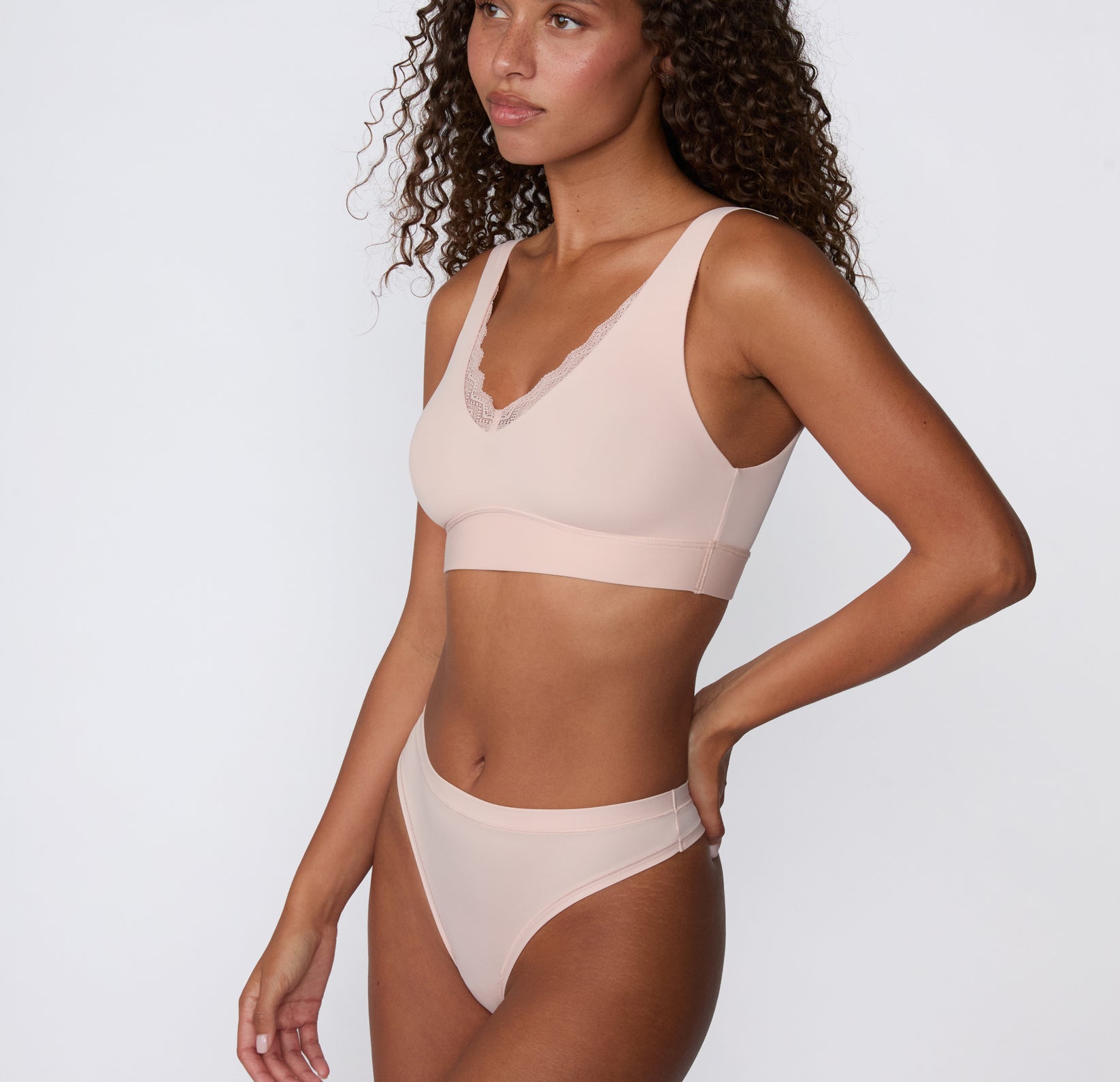 Angled side view on a white studio backdrop of the Bliss Thong in Ember Rose, featuring the lightweight microfiber fabric and streamlined fit.