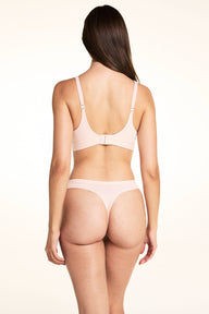 In a studio setting, Laura wears the Bliss Triangle Bralette and Bliss Thong in Rose, showing the adjustable straps, scoop back design, and thong silhouette with minimal back coverage.