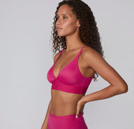 Side view on a white studio backdrop of a model wearing the Bliss Triangle Bralette in Winterberry, showing the wireless design, lightly lined cups, and smooth underband.
