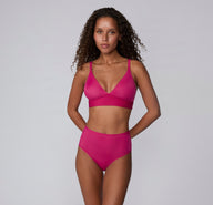 Full-body view on a white studio backdrop of a model wearing the Bliss Triangle Bralette and matching underwear in Winterberry, showing the coordinated set and minimalist design.