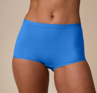 In a neutral studio setting, Nemesis wears the Bliss Boyshort in Bluebird, showing the smooth microfiber fabric and full-coverage front. sizing: Nemesis wears size Medium