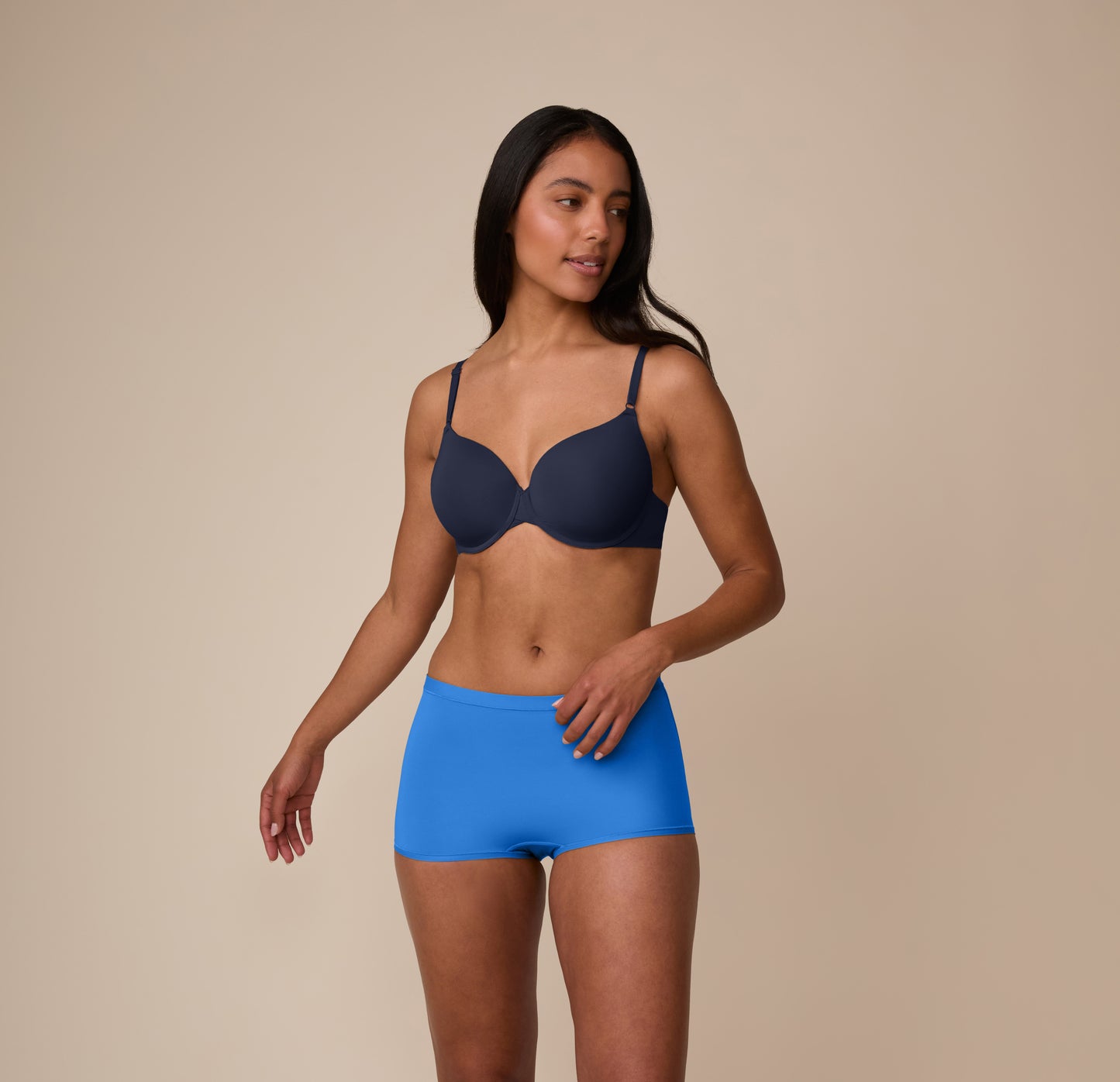 Nemesis wears the Bliss Boyshort in Bluebird, shown in a relaxed full-body pose on a neutral backdrop to display the smooth, lightweight fit.