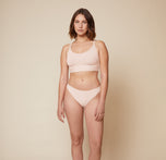 Carli standing with her arms relaxed by her sides, wearing the Bliss Racerback Bralette and Bliss Bikini in Rose. This front view showcases the full outfit, highlighting the supportive fit of the bralette and the bikini.