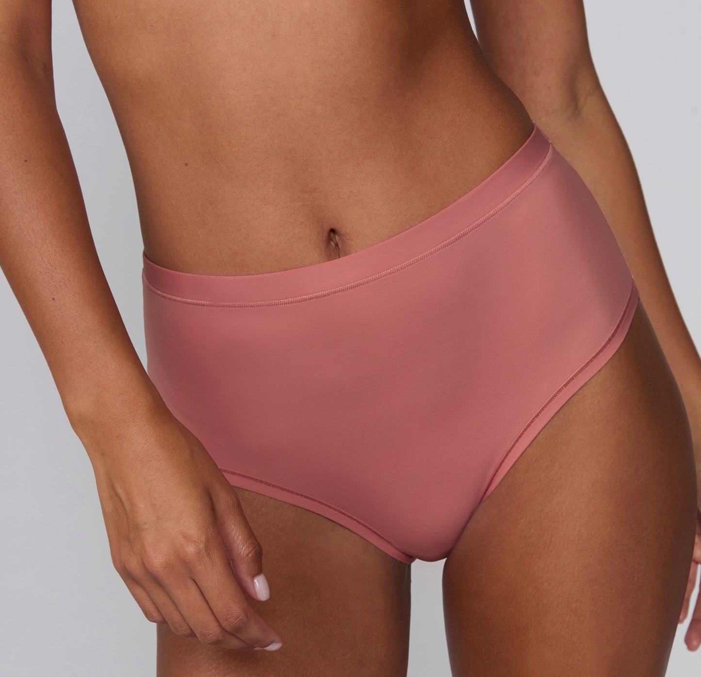On a light gray studio backdrop, Courtney wears the Bliss Highwaist in Cinnamon, shown from a front angle. The high-waisted underwear features a smooth waistband, full front coverage, and soft microfiber fabric designed for everyday comfort and a no-show feel under clothing.