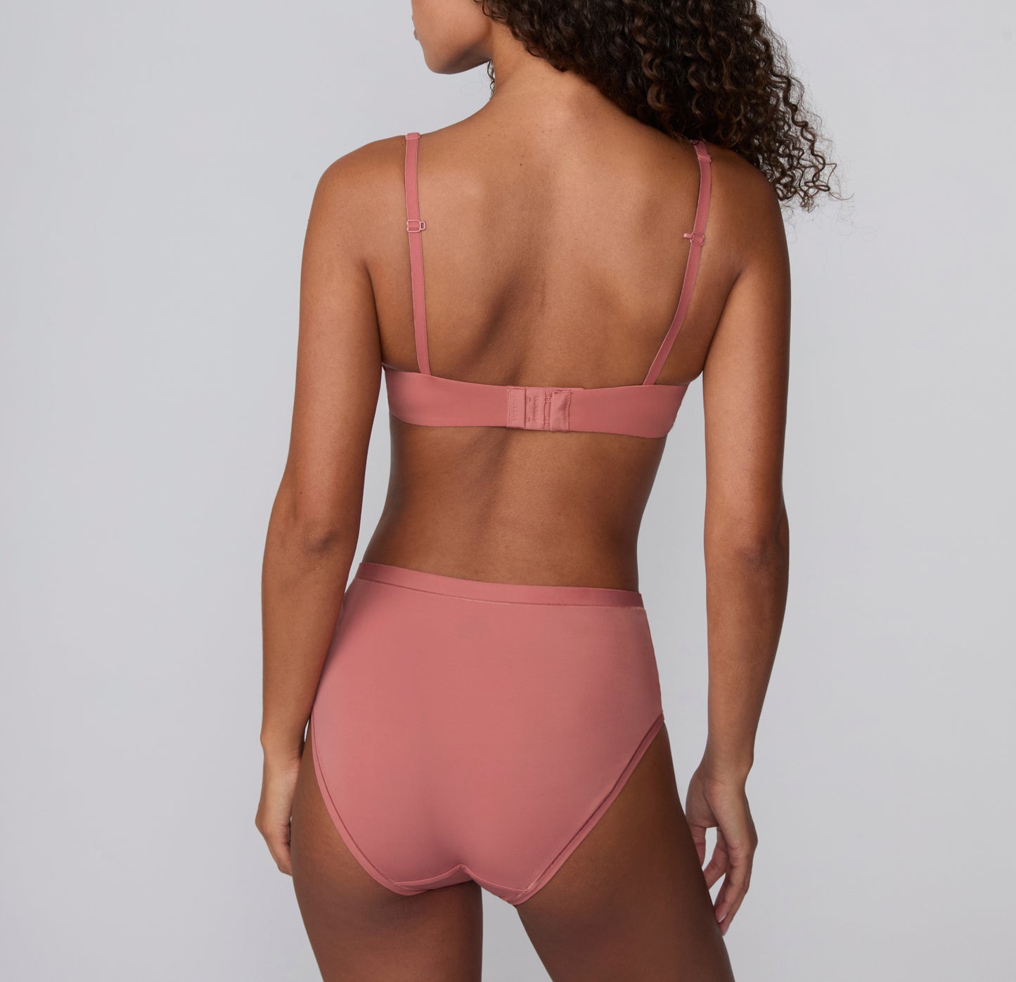 On a light gray studio backdrop, Courtney wears the Bliss Highwaist in Cinnamon, shown from the back. The high-waisted underwear features smooth, full back coverage and soft microfiber fabric designed for comfortable, everyday wear with a no-show feel under clothing.