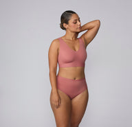 On a light gray studio backdrop, India wears the Bliss Highwaist in Cinnamon with a matching Bliss bralette. Shown in a full-body view, the high-waisted underwear features a smooth waistband, full coverage, and soft microfiber fabric designed for comfortable, everyday wear. sizing: India wears size Large