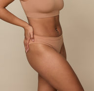Side angle of Jade in the Cloud Cotton Bikini in Dune. The flat seams and soft, breathable cotton-modal fabric ensure a barely-there feel.
