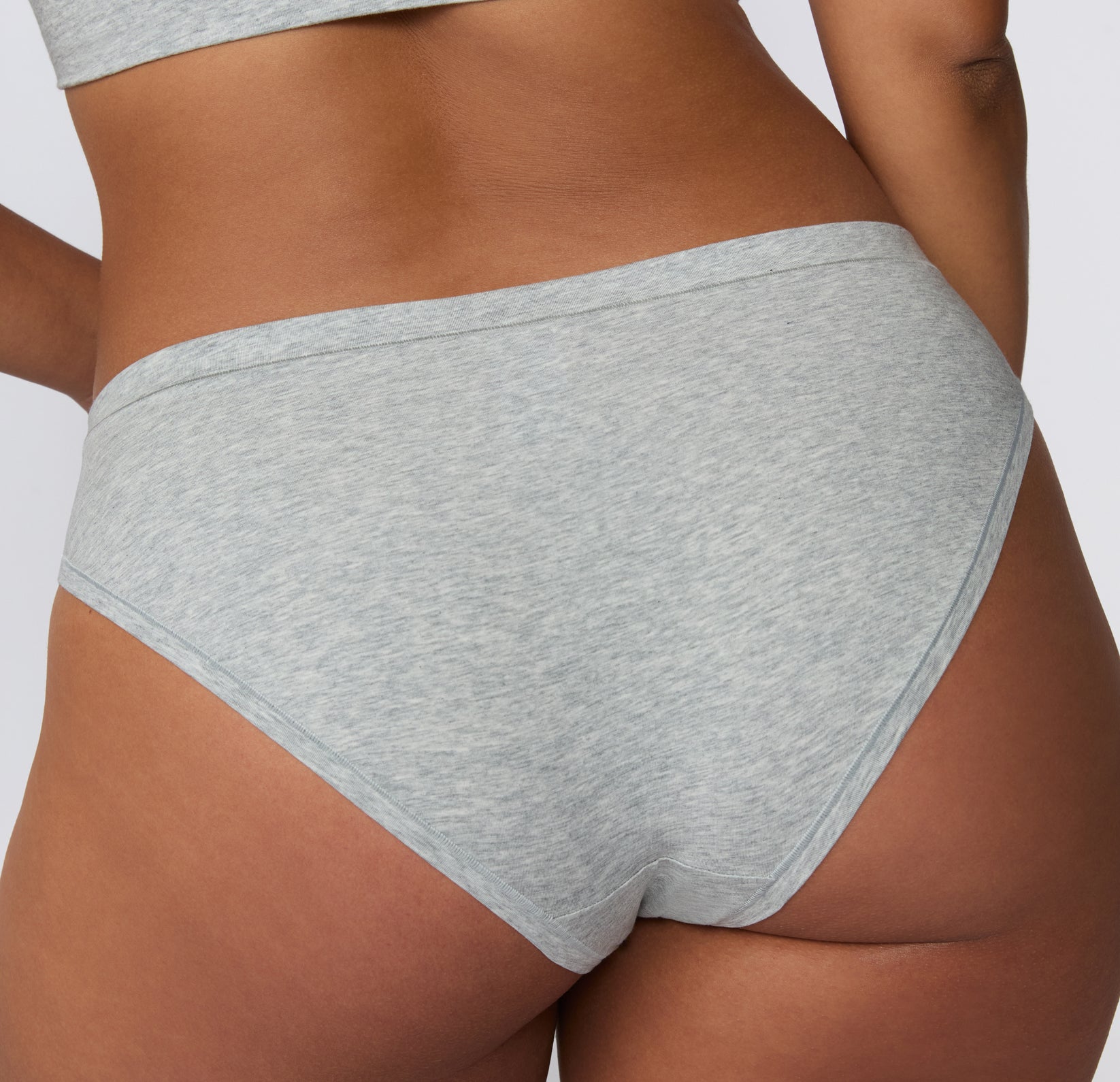 Back view on a light studio backdrop of the Cloud Cotton Bikini in Light Heather Grey, showing the smooth waistband, full back coverage, and soft cotton modal fabric.