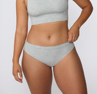 Front view on a light studio backdrop of the Cloud Cotton Bikini in Light Heather Grey, highlighting the low-rise waistband and smooth cotton modal fabric.