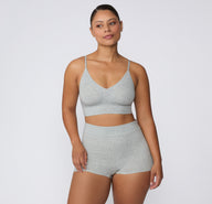 On a white studio backdrop, a model wears the Cloud Cotton Boyshort in Heather Grey with a matching bralette, showing the full set from a front-facing view and the soft, breathable cotton fabric.