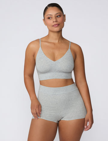 On a white studio backdrop, a model wears the Cloud Cotton Boyshort in Heather Grey with a matching bralette, showing the full set from a front-facing view and the soft, breathable cotton fabric.