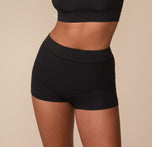 Side front view of Victoria wearing the Cloud Cotton Highwaist Boyshort in Black. The image emphasizes the wide waistband and full coverage fit that gently hugs the hips. sizing: Victoria wears size Medium