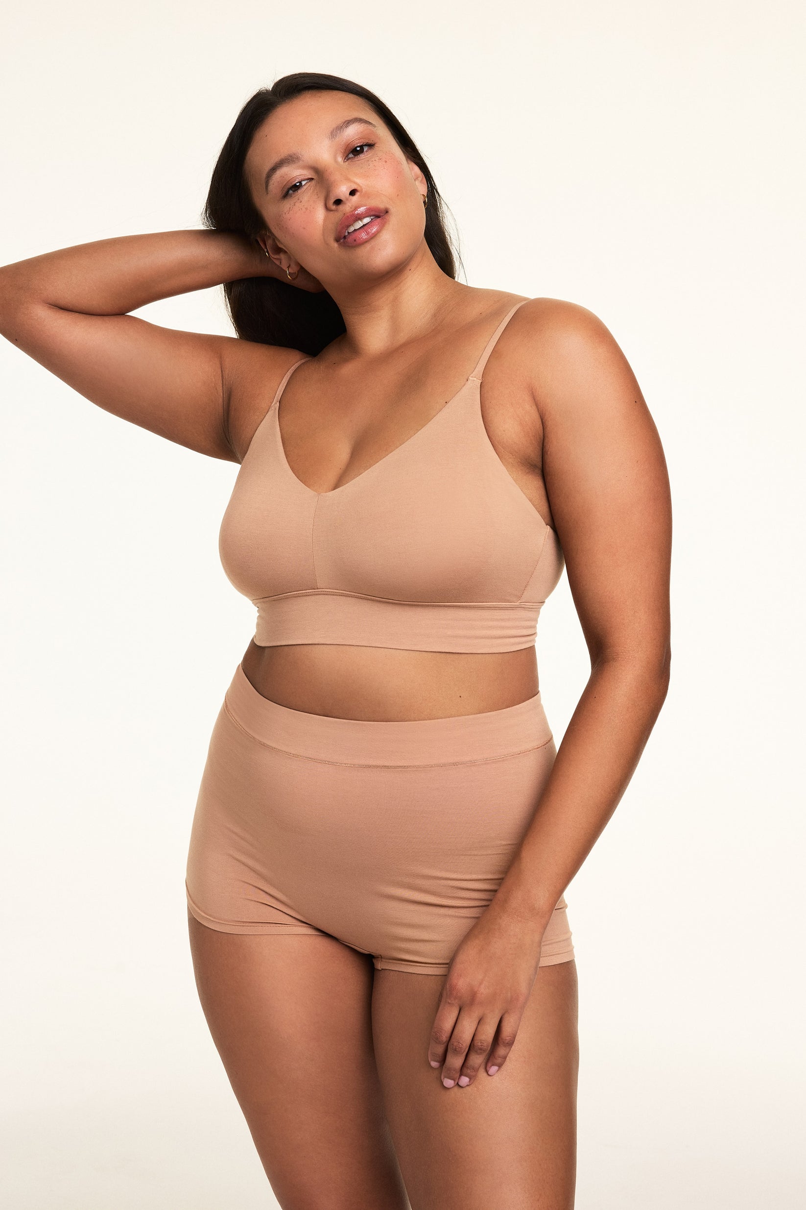 In a softly lit studio, Alana wears the Cloud Cotton Thin Strap Bralette and Cloud Cotton Highwaist Boyshort in Dune. The bralette features a square neckline, thin adjustable straps, and soft cotton modal fabric, paired with a high-waisted boyshort designed for full coverage and everyday comfort.