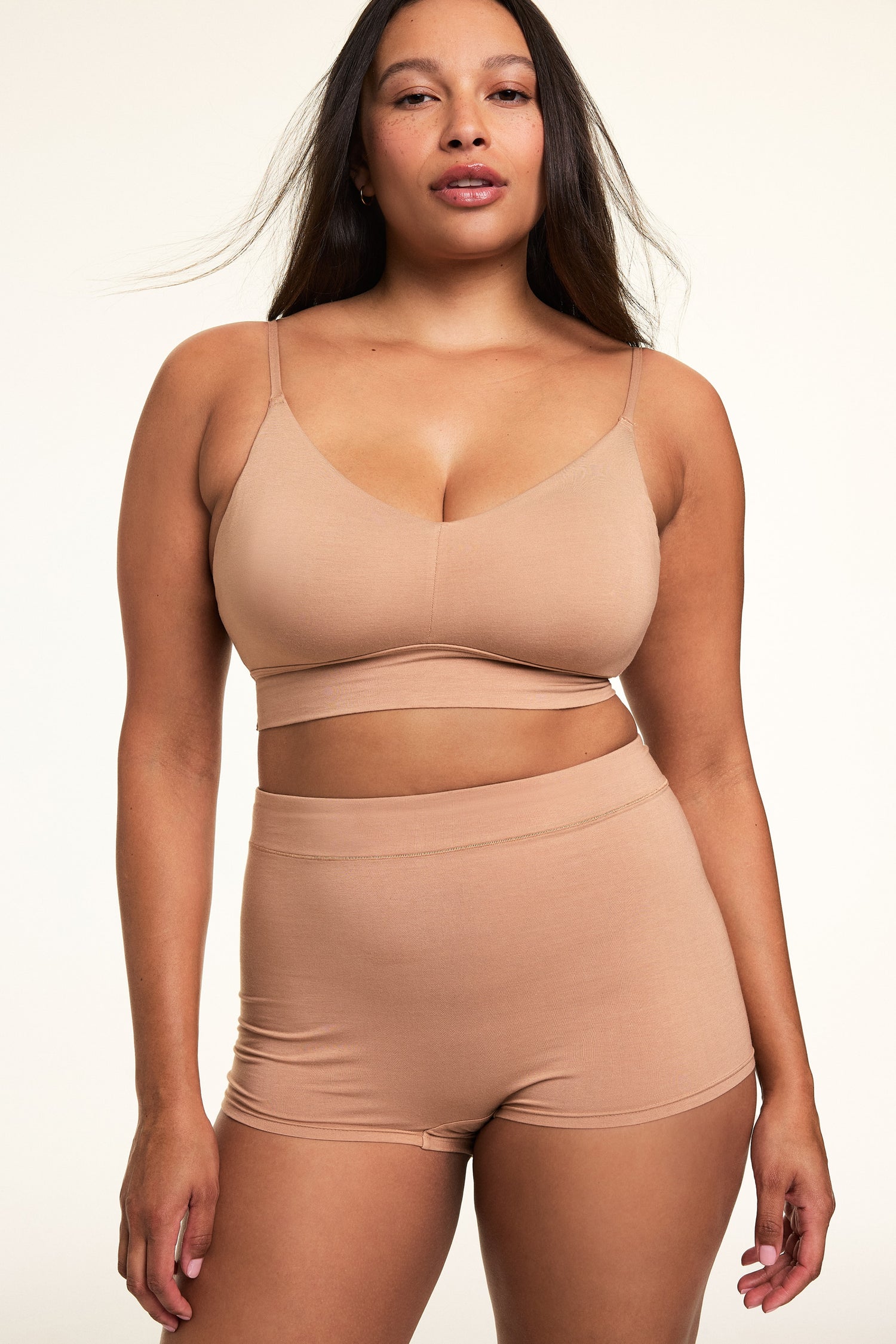In a softly lit studio, Alana wears the Cloud Cotton Thin Strap Bralette and Cloud Cotton Highwaist Boyshort in Dune. The bralette features a square neckline, thin adjustable straps, and soft cotton modal fabric, paired with a high-waisted boyshort designed for full coverage and everyday comfort. sizing: Alana wears a size Large
