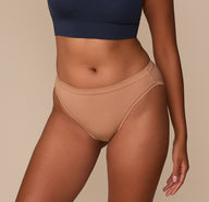 Close-up of Victoria wearing the Cloud Cotton French Cut Brief in Dune. The high-cut leg opening and mid-rise waistband are visible, highlighting the soft stretch-cotton fabric and comfortable fit. sizing: Victoria wears size Medium