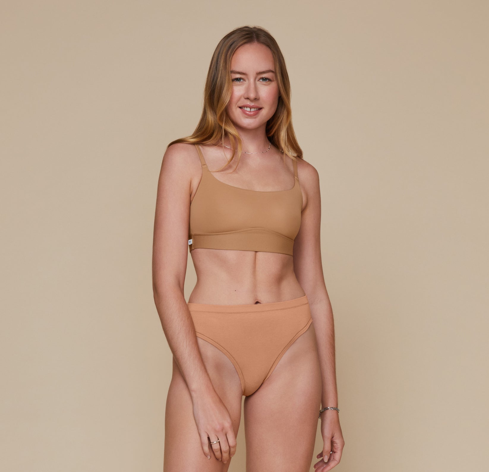 Front, full body view of Erin wearing the Bliss Scoop Bralette in the color Tan and the Cloud Cotton French Cut Brief in the color Dune.
