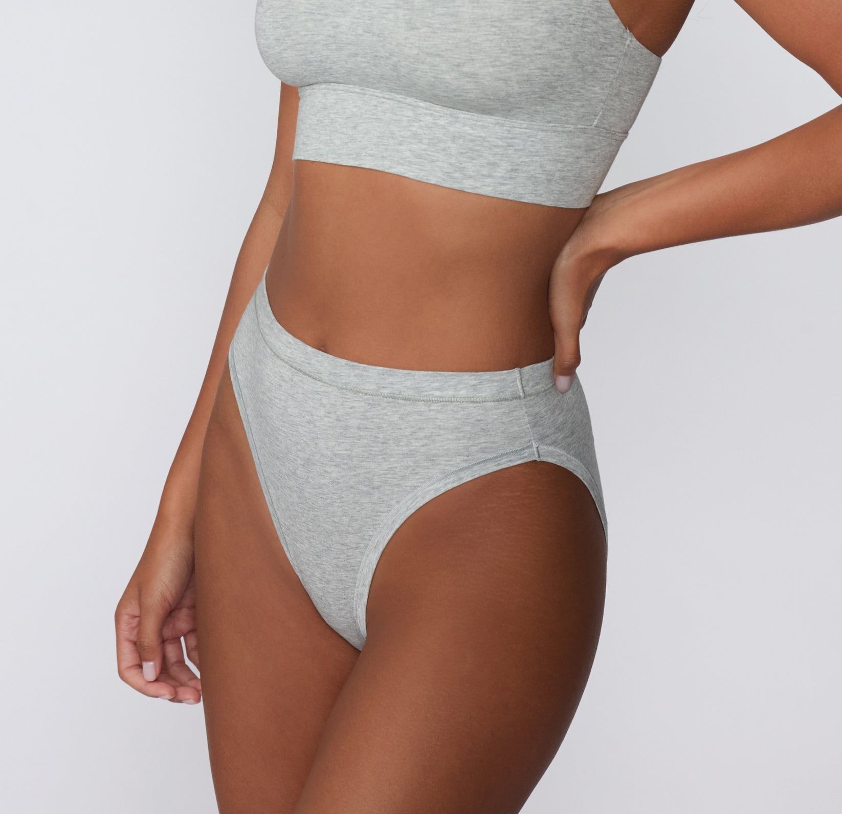 Angled side view on a light studio backdrop of the Cloud Cotton French Cut in Light Heather Grey, showing the high-leg silhouette and soft cotton modal fabric.