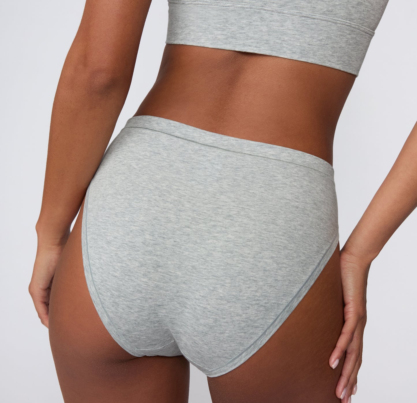 Back view on a light studio backdrop of the Cloud Cotton French Cut in Light Heather Grey, showing full back coverage and a smooth, clean waistband.