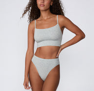 Full-body front view on a light studio backdrop of the Cloud Cotton French Cut in Light Heather Grey, paired with the Cloud Cotton Thin Strap Bralette.