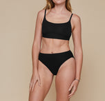 Front view of Model wearing Cloud Cotton French Cut Brief in Black and the matching Cloud Cotton Scoop Bralette in Black. The comfort and convenience of the set is emphasized.