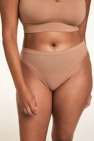 In a softly lit studio, Alana wears the Cloud Cotton Thin Strap Bralette and Cloud Cotton French Cut Brief in Dune. The high-rise brief features a high leg silhouette and soft cotton modal fabric designed for breathable, stay-put comfort.