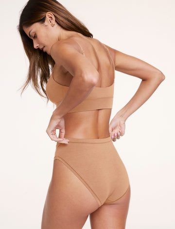 Side and back view of Linni wearing the Cloud Cotton Triangle Bralette and Cloud Cotton French Cut underwear in Dune, showing the adjustable straps, wide underband, and high-cut silhouette.