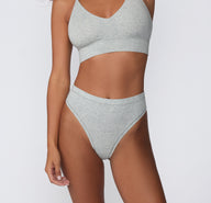 On a white studio backdrop, a cropped front view shows the Cloud Cotton Highwaist Thong in Heather Grey, focusing on the high-rise waistband and soft cotton modal construction.