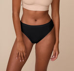 Front view of Victoria wearing the Cloud Cotton Highwaist Thong in Black. The image focuses on the soft, high-rise waistband and full front coverage made from breathable cotton fabric. sizing: Victoria wears size Medium