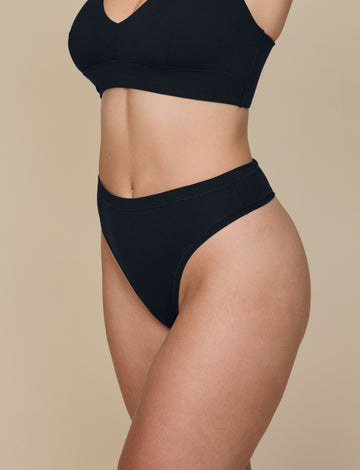Side angle of Summerlyn in the Cloud Cotton Highwaist Thong in Black. The silhouette shows the contoured waistband and soft, breathable cotton-modal fabric.