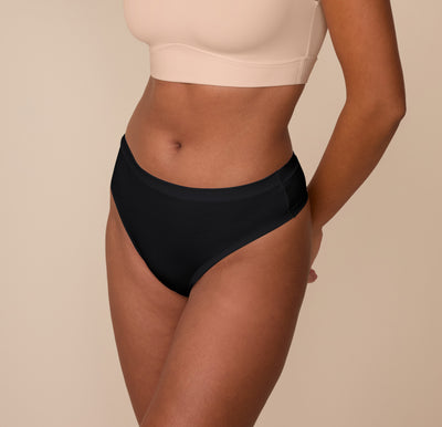 Side angle of Victoria wearing the Cloud Cotton Highwaist Thong in Black, highlighting the high-cut leg and sleek side seams.